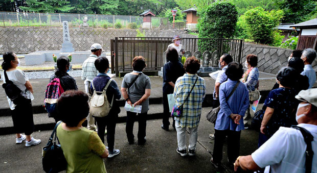 萬霊供養塔前で、地元の中澤支部長から、差別がない社会の実現に向けた塔建立の経過などを聞いた（7月21日・埼玉県美里町）